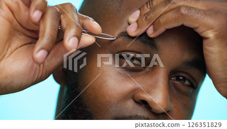 Man, face and closeup with tweezers for grooming, hands with plucking or hair removal on blue background. Portrait, hygiene and African male for treatment, tool and eyebrow maintenance in studio Man, face and closeup with tweezers for grooming, hands with plucking or hair removal on blue background. Portrait, hygiene and African male for treatment, tool and eyebrow maintenance in studio 126351829