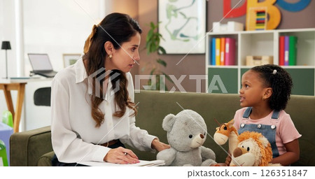 Psychologist, child and toys in office for mental health, therapy session and questions. Therapist woman, listen and girl for evaluation, clinic or consultation for patient support or development 126351847