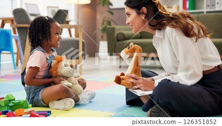 Psychology, woman and girl with teddy bear, talk or happy with clipboard for emotional assessment on floor. Person, therapist and child with toys, play and checklist for test at mental health clinic 126351852