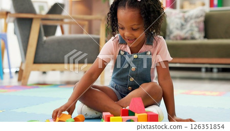Black girl, block and building with toys for playing or fun activity on floor at therapy office. Kid, child or student with shapes or assessment for playful learning, fine motor skills or education 126351854