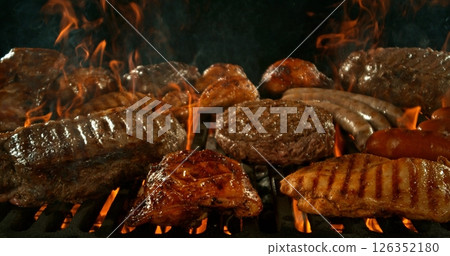 Different types of grilled meat on charcoal grill with Flames. Isolated on Black Background. Different types of grilled meat on charcoal grill with Flames. Isolated on Black Background. 126352180