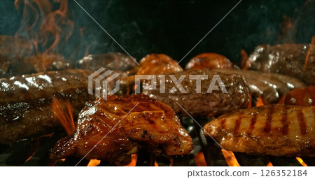 Different types of grilled meat on charcoal grill with Flames. Isolated on Black Background. 126352184