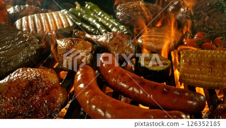 Different types of grilled meat and vegetable on charcoal grill with Flames. Isolated on Black Background. 126352185