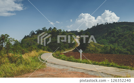 Curved road winding through forested mountain 126352240