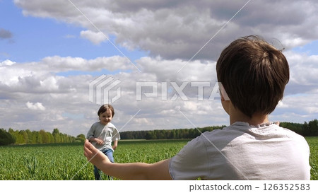Two brothers enjoy a joyful moment together. Two boys in a field in the spring, a small child runs into the arms of an older brother. Older brother and younger brother play together 126352583