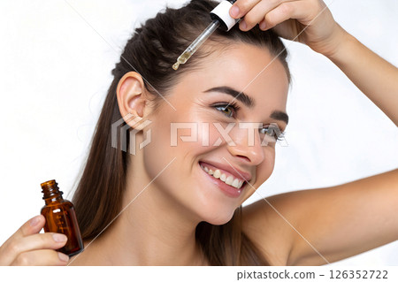 woman applying hair serum with pipette to scalp, haircare treatment with essential oil droplet, therapeutic hair restoration product application with glass dropper 126352722