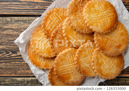 Tasty French shortbread cookie Sable Breton closeup on parchment paper on wooden table. Horizontal top view 126353000
