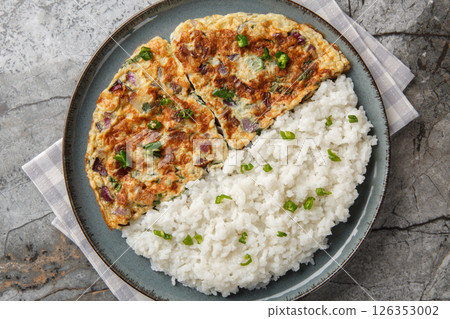 Motta Porichathu or Spicy Coconut Ginger Omelette with curry leaves, red onion, green chili, a little salt and pepper closeup on the plate. Horizontal top view 126353002