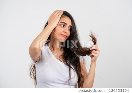 A young, beautiful but sad woman on a white background because her hair is unkempt and broken 126353104