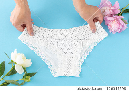 Women's hands with a white panties on the blue background. 126353298