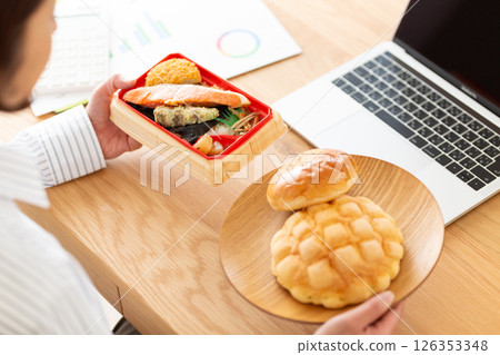 A middle-aged woman worrying about lunch at her desk in the office A middle-aged woman worrying about lunch at her desk in the office 126353348
