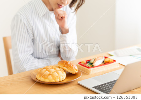 A middle-aged woman worrying about lunch at her desk in the office A middle-aged woman worrying about lunch at her desk in the office 126353395