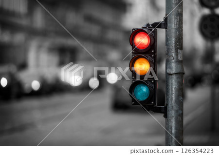 view of city traffic with traffic lights, in the foreground a semaphore with a red and orange light view of city traffic with traffic lights, in the foreground a semaphore with a red and orange light 126354223