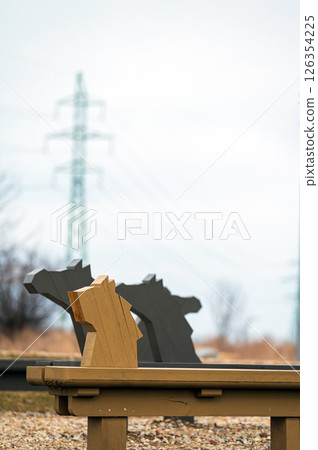Artistic benches shaped like horses near a serene lakeside in a tranquil park setting 126354225