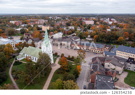 Aerial view of an Latvian town features a historic church and colorful autumn trees. 126354238