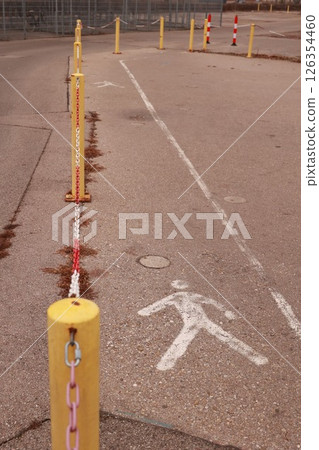 Yellow and white sign with a walking man on it is on the ground Yellow and white sign with a walking man on it is on the ground 126354460