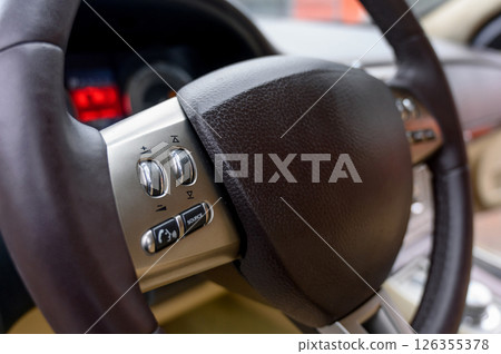 A close-up of a modern car's steering wheel with control buttons A close-up of a modern car's steering wheel with control buttons 126355378