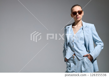 High fashion portrait of young confident female model in blue three-piece suit. Monochrome blue outfit 126355536