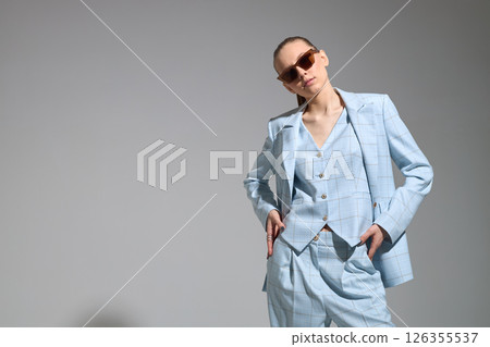 High fashion portrait of young confident female model in blue three-piece suit. Monochrome blue outfit 126355537