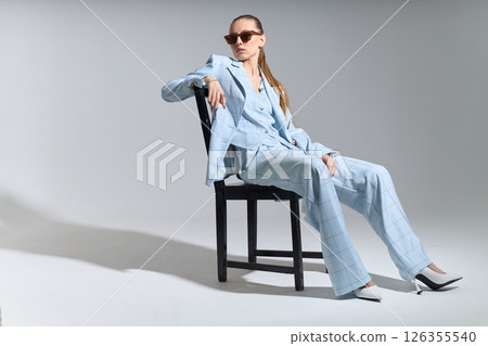 High fashion portrait of young confident female model in blue three-piece suit. Monochrome blue outfit 126355540