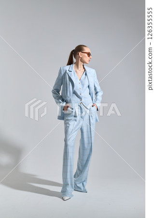 High fashion portrait of young confident female model in blue three-piece suit. Monochrome blue outfit 126355555