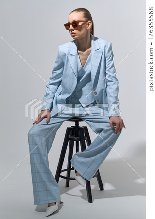 High fashion portrait of young confident female model in blue three-piece suit. Monochrome blue outfit High fashion portrait of young confident female model in blue three-piece suit. Monochrome blue outfit 126355568