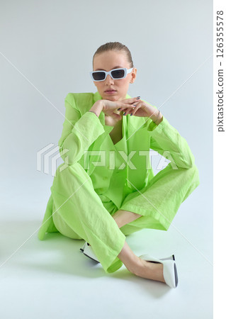 High fashion portrait of young confident female model in green lime color three-piece suit. Monochrome green outfit 126355578