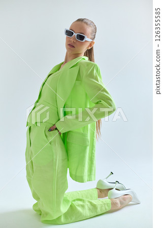 High fashion portrait of young confident female model in green lime color three-piece suit. Monochrome green outfit High fashion portrait of young confident female model in green lime color three-piece suit. Monochrome green outfit 126355585