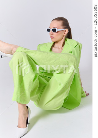 High fashion portrait of young confident female model in green lime color three-piece suit. Monochrome green outfit 126355608
