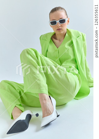 High fashion portrait of young confident female model in green lime color three-piece suit. Monochrome green outfit 126355611