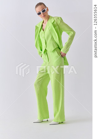 High fashion portrait of young confident female model in green lime color three-piece suit. Monochrome green outfit High fashion portrait of young confident female model in green lime color three-piece suit. Monochrome green outfit 126355614