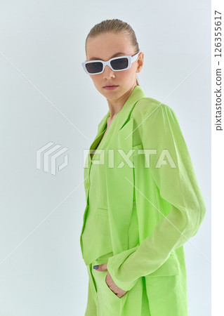 High fashion portrait of young confident female model in green lime color three-piece suit. Monochrome green outfit High fashion portrait of young confident female model in green lime color three-piece suit. Monochrome green outfit 126355617