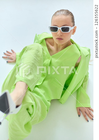 High fashion portrait of young confident female model in green lime color three-piece suit. Monochrome green outfit High fashion portrait of young confident female model in green lime color three-piece suit. Monochrome green outfit 126355622