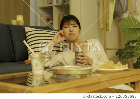 憤怒的年輕女子晚上在客廳喝酒 126355685