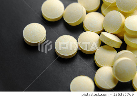 Pile of yellow painkiller pills on black ceramic surface. Macro shot. 126355769