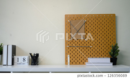Minimalist home office shelf with pegboard, books, stationery, and indoor plants 126356089