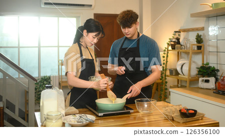 Happy couple wearing aprons preparing breakfast in modern kitchen 126356100