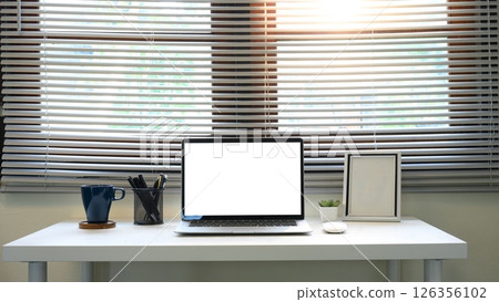 Contemporary home office desk with blank laptop screen in front of large window blinds Contemporary home office desk with blank laptop screen in front of large window blinds 126356102