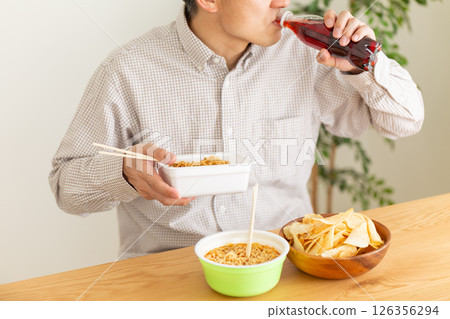 Middle-aged man binge eating junk food 126356294