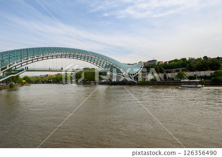 Peace bridge, steel and glass construction pedestrian bridge over Kura Mtkvari river in central Tbilisi, capital of Georgia 126356490