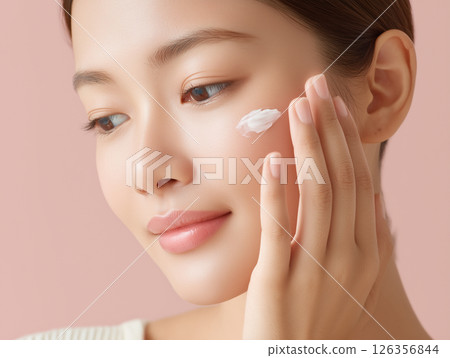 Hands of a Japanese woman applying moisturizing cream to her face as part of skin care 126356844