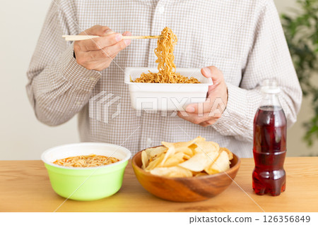 Middle-aged man binge eating junk food Middle-aged man binge eating junk food 126356849