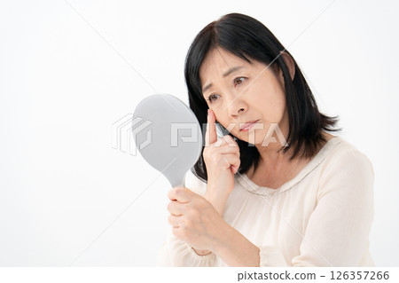 Senior woman looking in the mirror worries Senior woman looking in the mirror worries 126357266