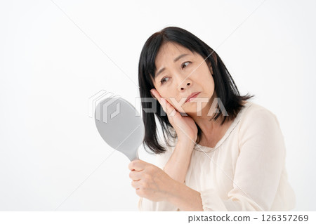 Senior woman looking in the mirror worries Senior woman looking in the mirror worries 126357269