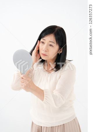Senior woman looking in the mirror worries 126357273
