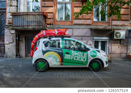 Restaurant delivery vehicle. The compact car is painted with advertising and a decorative shrimp on the roof. 126357524