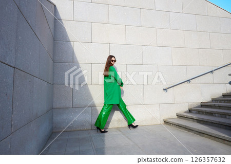 High fashion photo of a young brunette woman in green coat, poloneck and leather pants. High fashion photo of a young brunette woman in green coat, poloneck and leather pants. 126357632