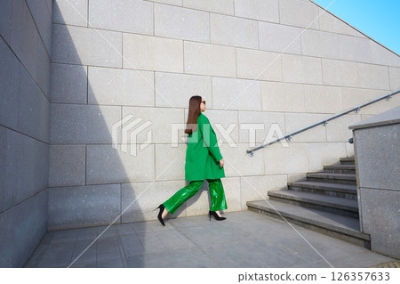 High fashion photo of a young brunette woman in green coat, poloneck and leather pants. High fashion photo of a young brunette woman in green coat, poloneck and leather pants. 126357633