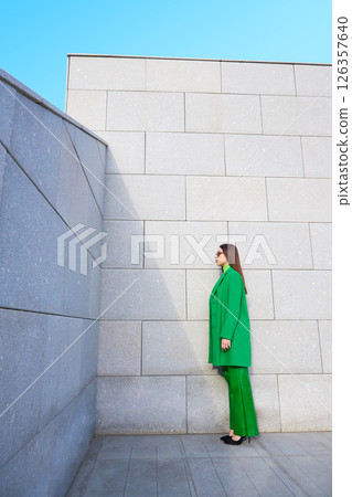 High fashion photo of a young brunette woman in green coat, poloneck and leather pants. High fashion photo of a young brunette woman in green coat, poloneck and leather pants. 126357640