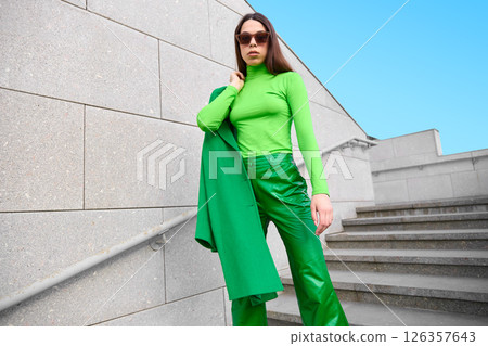 High fashion photo of a young brunette woman in green coat, poloneck and leather pants. High fashion photo of a young brunette woman in green coat, poloneck and leather pants. 126357643